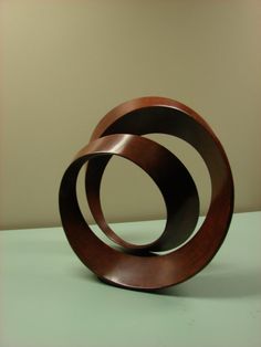 two metal rings sitting on top of a white table next to each other, one is brown and the other is black