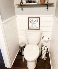 a white toilet sitting inside of a bathroom next to a wooden shelf filled with items