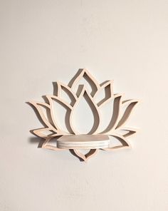 a white wall mounted clock with a wooden lotus design on it's face and bottom