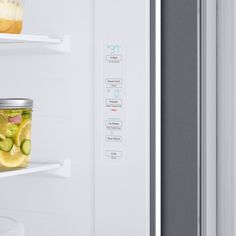 an open refrigerator door with pickles and lemons in the jar on the shelf