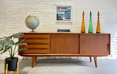 a wooden sideboard sitting next to a potted plant on top of a table