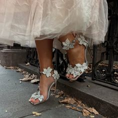 a bride's feet in high heels with flowers on the toes and dress underneath