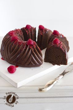 a chocolate bundt cake with raspberries on top and a slice cut out