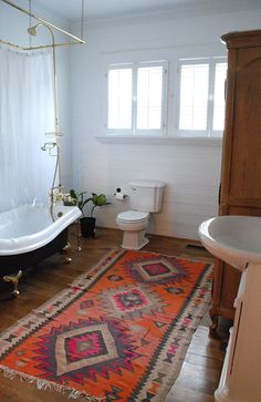 a bathroom with a rug, tub and toilet