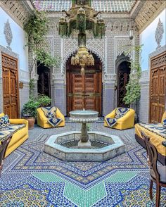 an ornate courtyard with yellow couches and blue patterned tiles on the floor, surrounded by potted plants