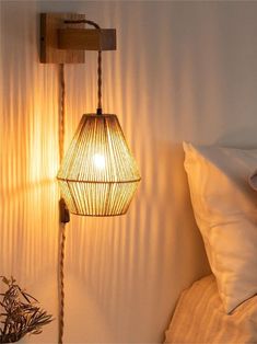 a lamp that is on the side of a wall next to a bed with pillows