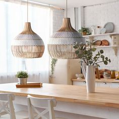 two lamps hanging over a kitchen counter next to a potted plant on top of a wooden table