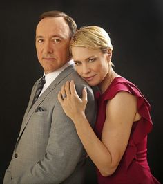 a man in a suit hugging a woman wearing a red dress with her arm around him