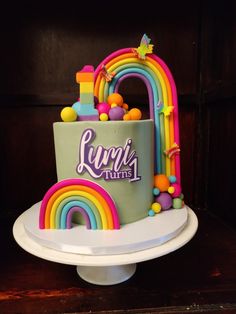 there is a cake that has been decorated with rainbows and letters on the side