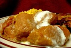 a white plate topped with meatballs covered in sauce and cream next to corn on the side