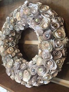 a wreath made out of rolled up paper flowers on top of a wooden bench in front of a window