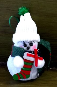 a snowman ornament with a green and red stocking around it's neck