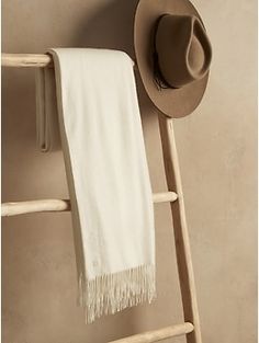 a hat, towel and wooden ladder against a wall