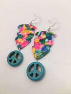 two peace signs are hanging from the back of some earring sets with flowers on them