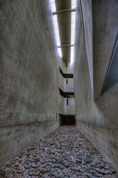 a long narrow hallway with light coming in from the ceiling and some rocks on the floor