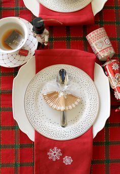 the table is set for christmas dinner with red napkins and silverware