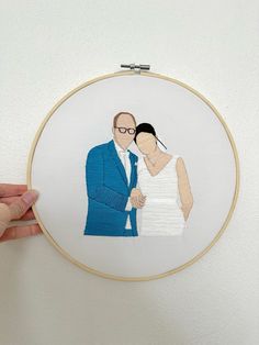 a man and woman are holding each other in front of a embroidery hoop