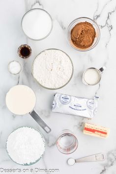 the ingredients to make chocolate cake are laid out on a marble counter top, including flour, eggs, butter, and sugar