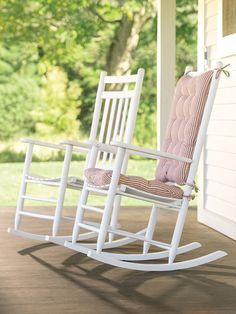 a white rocking chair sitting on top of a wooden porch