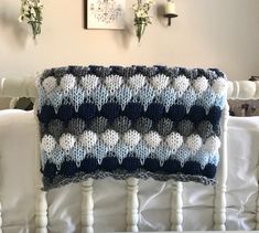 a crocheted blanket sitting on top of a white bed