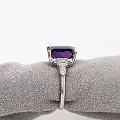 This Deep Purple Amethyst Ring is an elegant and timeless accessory crafted in solid 14k white gold. The emerald cut 10x8mm center stone is highlighted by sparkling baguette diamond accents. Perfect for February birthdays or to make a statement. Designer Silver Jewellery, Purple Amethyst Ring, Jewelry Showcases, Ruby Sapphire, Timeless Accessories, Earring Findings, Baguette Diamond, Pendant Bracelet, Amethyst Ring