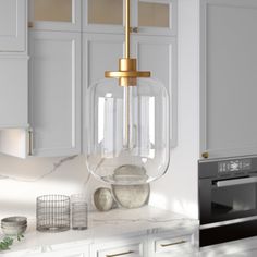 a kitchen with white cabinets and a gold colored light fixture hanging from the ceiling above it