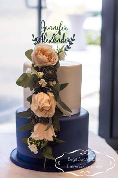 a three tiered wedding cake with flowers on top