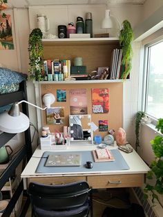 a desk with a laptop and some books on it in front of a large window