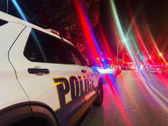 police cars are parked on the side of the road at night with bright colored lights