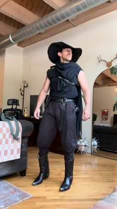 a man wearing a black hat and boots standing in a living room