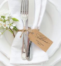 a white plate topped with a fork and knife next to a tag that says welcome