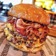 a bacon cheeseburger is sitting on top of a wrapper at a restaurant