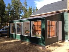 a small green building with windows on the side and red frame around the window sill