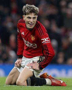 a soccer player sitting on the ground with his hands in his pockets and mouth open