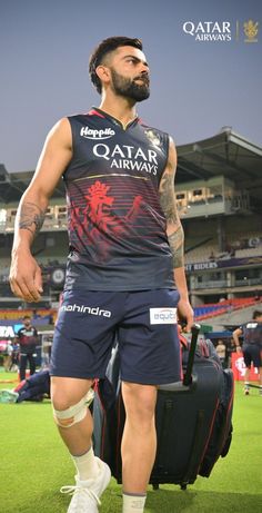 a man standing on top of a soccer field holding a luggage bag in his hand