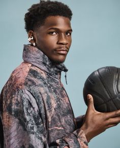 a man holding a basketball in his right hand and wearing earrings on the other