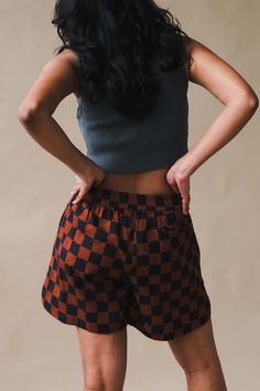 Dushyant brown and black checkered boxer shorts with dolphin hem small side slits pockets and elastic waistband. made exclusively for p&r. pair with the matching shirt for a full set.    100% cotton twill.    komal is 5'4" and wearing a size s. Plaid Pajama Shorts With Elastic Waistband, Brown Shorts With Elastic Waistband, Brown Short Bottoms With Elastic Waistband, Plaid Bottoms With Elastic Waistband, Short Brown Bottoms With Elastic Waistband, Plaid Bottoms With Elastic Waistband And Short Length, Brown Elastic Waistband Shorts, Brown Cotton Beachwear Bottoms, Denim Jacket With Dress