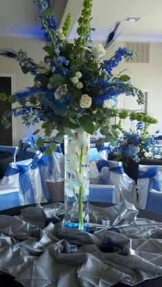 a vase filled with flowers on top of a table covered in blue and white ribbons