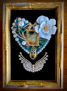 an ornate heart shaped brooch with flowers and pearls in gold frame on black background