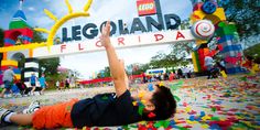 a little boy laying on the ground in front of a sign that says legoland florida