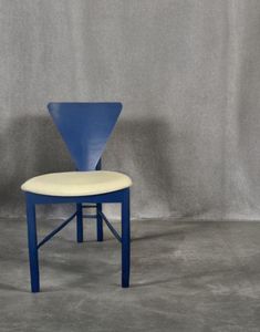 a blue and white chair sitting on top of a cement floor next to a gray wall