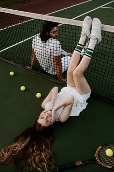 a woman laying on the ground with tennis rackets and balls in front of her