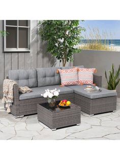 an outdoor sectional sofa set with pillows on the top and side tables in front of it