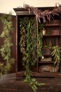 an old bookcase is decorated with christmas greenery