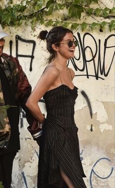 a woman standing next to a man in front of a wall with graffiti on it