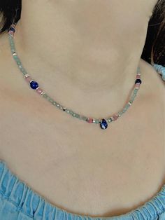 a woman wearing a necklace with blue beads and pink glass bead on it's neck