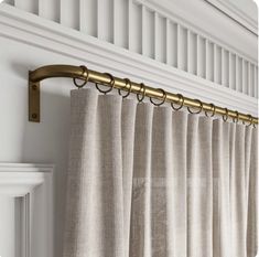 the curtain rod is attached to the side of a window with gold metal hardware on it