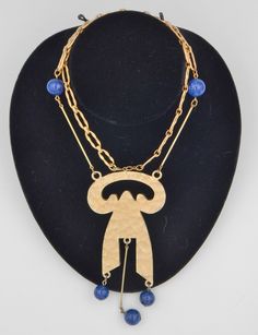 Mid-century modern, with a delightful arts and crafts feel. Napier captured the perfect blend of two artistic eras. And then that design into a statement necklace. This necklace is not only the cat's meow, but also the cat's pajamas! An amazing forged-like open link chain begins the journey of beauty. As the links travel down, two molted blue, Lapis-like, glass beads catch the eye. But it is the pendant, that captivates the eye and makes you catch your breath as you gaze upon the hammered free-f Vintage Blue Jewelry With Unique Variations, Artisan Blue Necklace With Artistic Design, Artisan Blue Metal Necklace, Mid-century Gold Necklace Gift, Antique Blue Brass Necklace, Luxury Hallmarked Modernist Necklace, Artisan Multi-strand Blue Necklaces, Collectible Modernist Pendant Necklace, Cat Pajamas