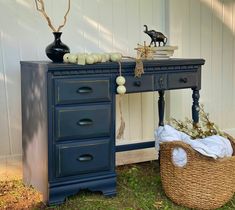 a blue desk with two drawers and a wicker basket on the ground next to it