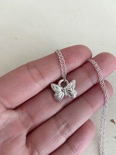 "Small butterfly charm handcrafted in fine 99.9% silver. Dainty but full of details.  This charm is completely carved by hand and polished up to a high shine. Measuring .5\" and hung from an adjustable 16-18\" nickel free silver chain." Handmade Sterling Silver Pendant Charm Necklace, Dainty Silver Engraved Charm Necklaces, Dainty Silver Engraved Charm Necklace, Tiny Butterfly Sterling Silver Jewelry, Tiny Sterling Silver Butterfly Jewelry, Small Sterling Silver Charm Necklace, Sterling Silver White Gold Jewelry With Butterfly Charm, White Gold Necklace With Butterfly Charm, White Gold Necklace With Butterfly Charm In Sterling Silver